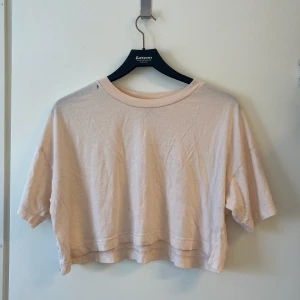 Ljusrosa top från Weekday  - En ljusrosa top/t-shirt från weekday, har ett litet litet hål upp vid axeln men det är lätt att sy. Använt ett fåtal gånger. Köparen står för frakten om ni inte bor i närheten och vill mötas upp. 