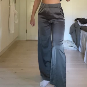 Mörkgrå satinbyxor - Säljer dessa mörkgrå satinbyxor från Gina, 100kr + frakt