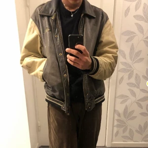 Vintage Varsity Jacket - Vintage Peak Performance varsity jacka i äkta läder. Varm och perfekt för kalla perioder. Väldigt sällsynt jacka som inte går att hitta online. Storlek L men sitter mellan M-L. Passar mig som är 180cm perfekt. Finns små defekter som fläckar och små hål. Hålen märker man inte (finns en i vänster ficka och längst ut på höger arm) och fläckarna tycker jag ger jackan karaktär. Kan skicka bild på defekterna i pm! Möts i Malmö och tar swish. Frakt står inte jag för (: