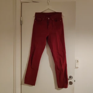 Röda Höga Jeans - Ett par högamidjade röda jeans med knappar i gylfen. 