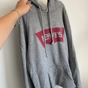Levi’s Hoodie - En jättesnygg Levi’s hoodie som användes en del för ett par år sedan, den är uppvikt nedtill för att den var stor i modellen. På bild 3 ser man två hål som sitter på inre sidan av ärmen och det andra långt ner vid höften ungefär. Dom är knappt märkbara🥰