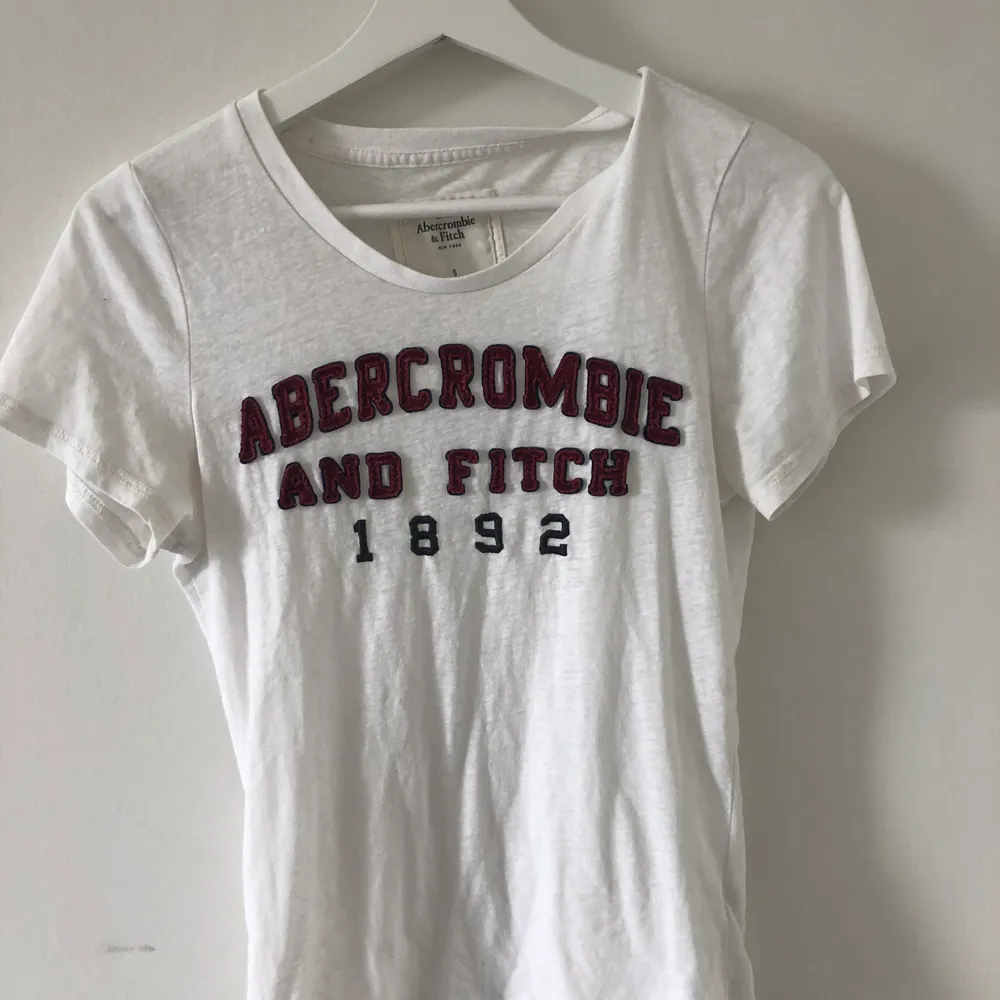 Vit T-shirt från Abercrombie med Tryck. Använd ett fåtal gånger, i fint skick✨ 70 kr + frakt. T-shirts.