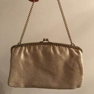 HANDVÄSKA - Liten gullig handväska som skimrar i guld, olika mycket i olika ljus. Du får plast med allt det viktigaste. Några små fläckar på (se bild 2) men de syns knapps. Väskan är ca 19 cm bred och ca 13 cm hög. Frakten ingår!💗