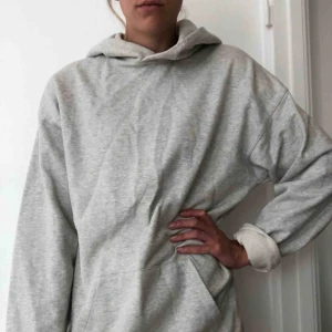  - En oversize hoodie med luva i ljusgrå bomull. 