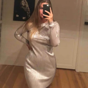  - fint klänning med reflekterande silvrig material från Nelly, aldrig använd och har fortfarande prislappen kvar. Köparen står för frakt😛