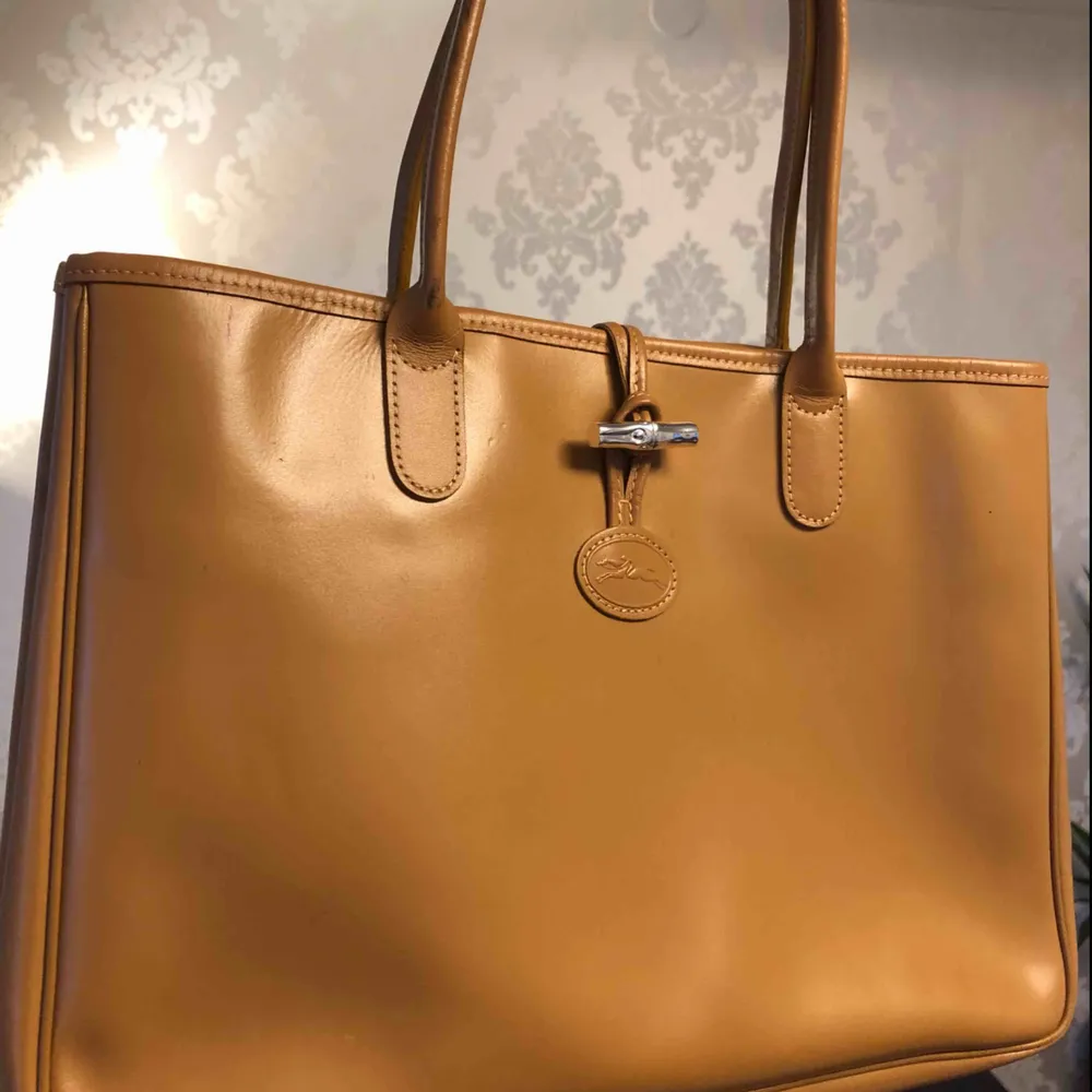 Äkta Longchamp leder väska. Har en liten defekt på sidan (som visas på bilden) Butik pris 4000kr.. Väskor.