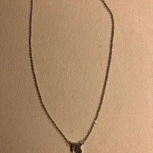 Ett silverfärgat halsband med tecknet för stjärntecknet jungfrun/virgo ♍️ 