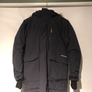 Didriksons - Mörkblå, vattentät, varm, bra skick, 4 fickor+ en nätficka på insidan, varmt material på övre delen av ryggen och ”päls” runt luvan. Pris går att diskutera.