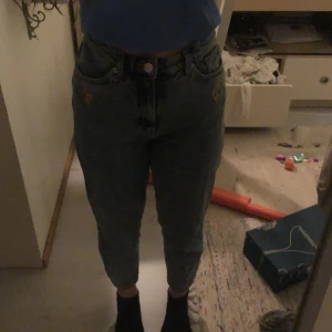 mom jeans från monki - VÄLDIGT BILLIGT OCH PRIS KAN DISKUTERAS!!! supersnygga momjeans från monki! väldigt fint skick. det är blomdetaljer inbroderat vid fickorna, kontakta för mer bilder. högmidjade och lite lösa vid smalbenen. nypris 500kr men säljer för 40+frakt 🤍