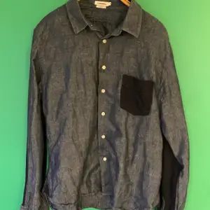Skjorta från J. Lindeberg i denim med mörkblå detaljer på ficka och armbågar stl XL slim fit (liten i storleken). 
