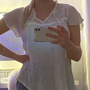 Vit topp - 🤍Vit topp med snörning i kragen och diskreta volanger, detalj i nacken, storlek S, OBS tunnt tyg-genomskinlig 