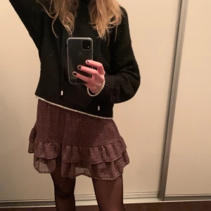 Volang kjol - En jättefin mönstrad volangkjol i vinröd, svart och vit. Det är ett silvrit pärlband längst ner. Det passar till allt och du kan ha den på vintern!!! Den är också jätteskön. Den är i fint skick. Jag skulle säga att den motsvarar XS/S.