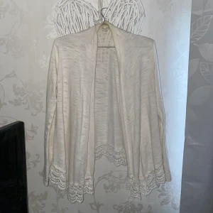 Vit kofta - En tunn vit kofta med spetskant från Lindex. Den är som en xs i storleken. Den är i jättefint skick, förutom lite smink uppe vid ”kragen” men jag tvättar den innan så att det försvinner såklart 💗frakten är inkluderad i priset.  kram 