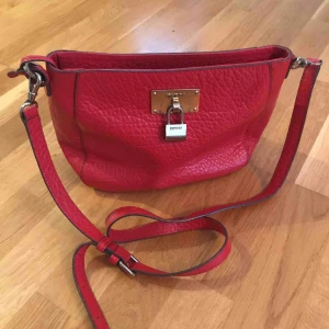 - Röd DKNY axelremsväska. Slitningar på metallbrickan.(se bild) 