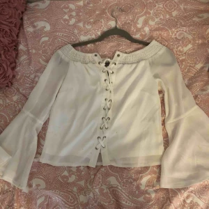  - En vit blus med snörning och utsvängda armar 