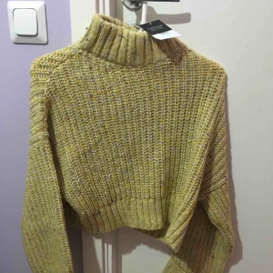  - Senapsgul stickad tröja i kort modell. Nyligen inköpt men aldrig använd, prislappen sitter på. Stl 38 passar en S. 