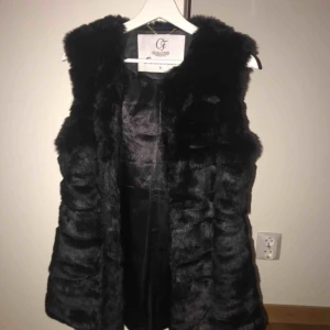  - En svart pälsväst som är fake päls