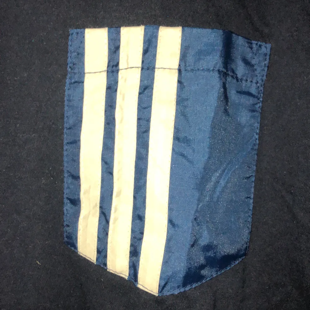 En blå t-shirt köpt på beyond retro. Adidas fickan är påsydd från tidigare. Det står storlek XS men skulle säga att den är i S/M. T-shirts.