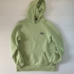 Grön stüssy hoodie - Något urtvättad och har en liten blå fläck på ena ärmen, annars i bra skick. Säljer pga att jag inte använder den längre. Frakten ingår i priset