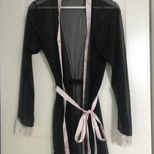 Genomskinlig kimono med spets och stenar längst ut på armarna. Aldrig använd
