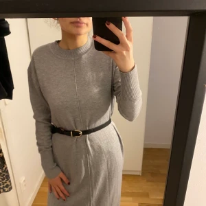 Stickad lång klänning - Den här knälånga klänningen har 2 öppningar vid sidan. Lite stor så bälte borde användas. Storlek S