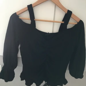 En svart mag tröja  - Tröja har lite volanger vid midjan men också i armarna, Men passar all stil, men mest till jeans, och har används ett få antal gånger 