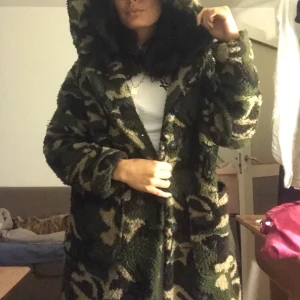 Militär Teddy Jacket  - Lång teddyjacka med luva. Militärmilerad. Mycket använd där av priset men är fortfarande i bra skick. Använd 2 säsonger. Väldigt varm och mysig jacka. 