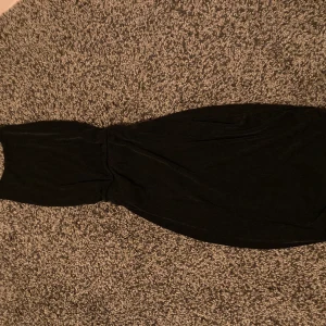 Klänning med öppen rygg - Klänning med öppen rygg och snörning baktill. Lite glittrig i materialet. 