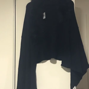 Svart poncho  - Helt ny och oanvänd.