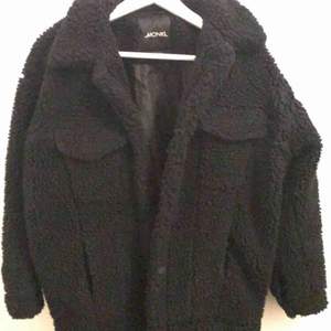 En svart teddy jacka från monki med fickor på båda brösten