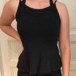  - Fint svart linne med en volang längst nere, passar upp till en S