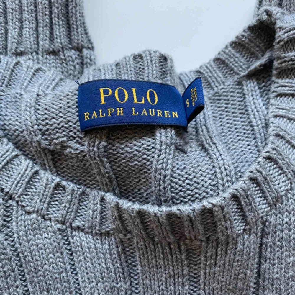 Kabelstickad Ralph Lauren Polo i nyskick. Som ni ser är det inga nopprar eller sånt som uppkommit efter användning då den är oanvänd. Mörkgrå och jättemysig, köpt för ca 1000 kronor, . Tröjor & Koftor.