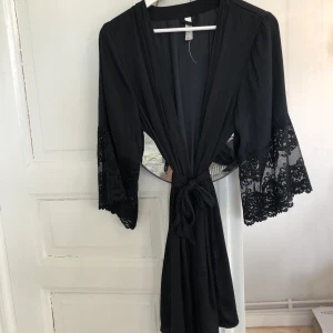 Kimono - Superfin kimono i ett satinliknande material, spets på armarna. Helt oanvänd. Köparen står för frakten. 