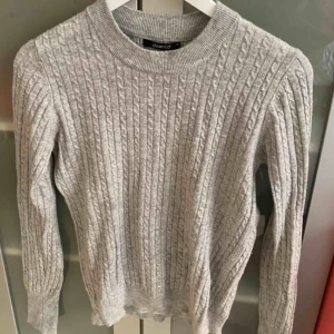  - En grå stickad tröja som har bra kvalitet som inte är sönder någon stans 
