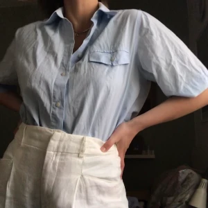 Vintage kortärmad blå skjorta - Blå kortärmad skjorta som med fördel bärs oversized, instoppade i högmidjade byxor. Knappt använd! FRI FRAKT :)