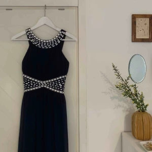  - Balklänning i en marinblå/mörkblå färg (ser nästan svart ut på bilderna men den är blå). Tyget i ryggen är stretchigt så tror att den kan passa upp till M, själv har jag S. Endast använd två gånger. Frakt tillkommer. 