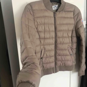  - Vindjacka i en beige/ljusbrun färg. Aldrig använd, säljs för 180kr plus frakt.