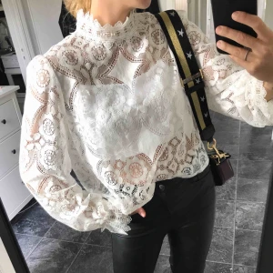  - Vit blus i vacker spets från Zara. Strl M men passar även en S. Knappar i nacken, lose fit modell och klockade ärmar. Aldrig använd så i superfint skick. Köparen står för frakten 🕊