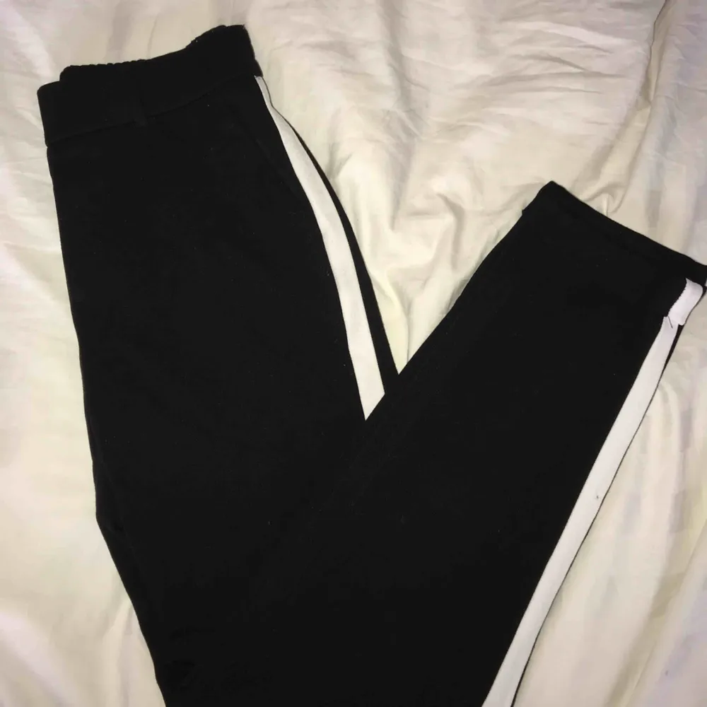 Ett par svarta kostymbyxor med vita ränder på sidorna från Vero Moda. Lite kortare i modellen. Använda 2-3ggr så därför väldigt fint skick!! Inköpta för cirka 199kr säljer för 99kr. Köpare står för frakt🥰🥰🥰. Jeans & Byxor.