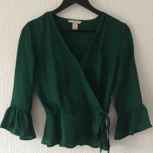  - Knappt använd topp från H&M. Storlek 32 men passar mig som är en 34. Omlott med en hake+annat fäste på insidan och snörning på utsidan. Lite volang på ärmarna och fint mönstrat tyg. Fraktkostnad tillkommer, kan också mötas upp i Malmö