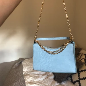 Väska Mango - Ljusblå väska med gulddetaljer från mango. Kommer ej till användning. 150 kr + 66 kr frakt 