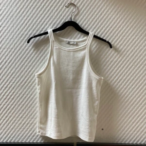 Vitt linne med hög krage från Nelly - 🤍 vitt, ribbat och trendigt linne från Nelly. aldrig använt. storlek XS-S. 🤍