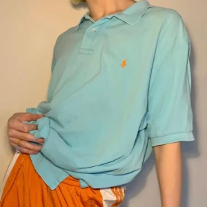 Oversized turkos Ralph Lauren halv button up - Superskön vintage turkos Ralph Lauren half button up i storleken XXL för att få en oversized siluett 🧡 Orange broderad logga på vänster bröst och två slits på vardera sida som en extra spicy detalj! Så snygg statement piece eller skön som ett mjukisplagg för extra bekvämlighet!  