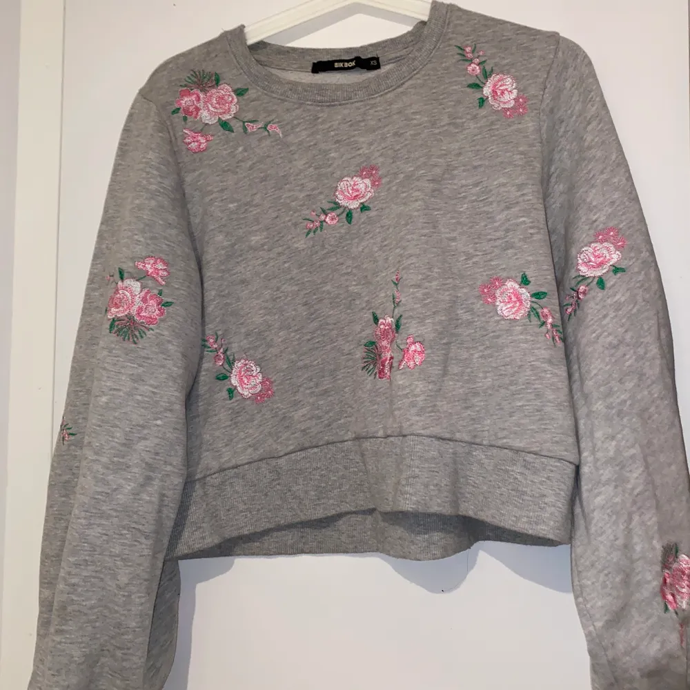 grå mjukis tröja med rosa blommor på, har använt fåtal gånger och i bra skick. Hoodies.
