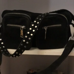 Noella väska - Celina svart är en av Noellas populäraste modeller av Crossover väska i svart med rem som har två rader med nitar. Denna crossover-väska kan även bäras som en Crossbody-väska. Den är använd några gånger fast den är ändå hyfsat ny. Den kostar egentligen 700 kronor  