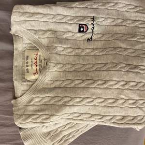 En ljusgrå flätstickad bondelid tröja. Sparsamt använd och är därmed i ett bra skick!