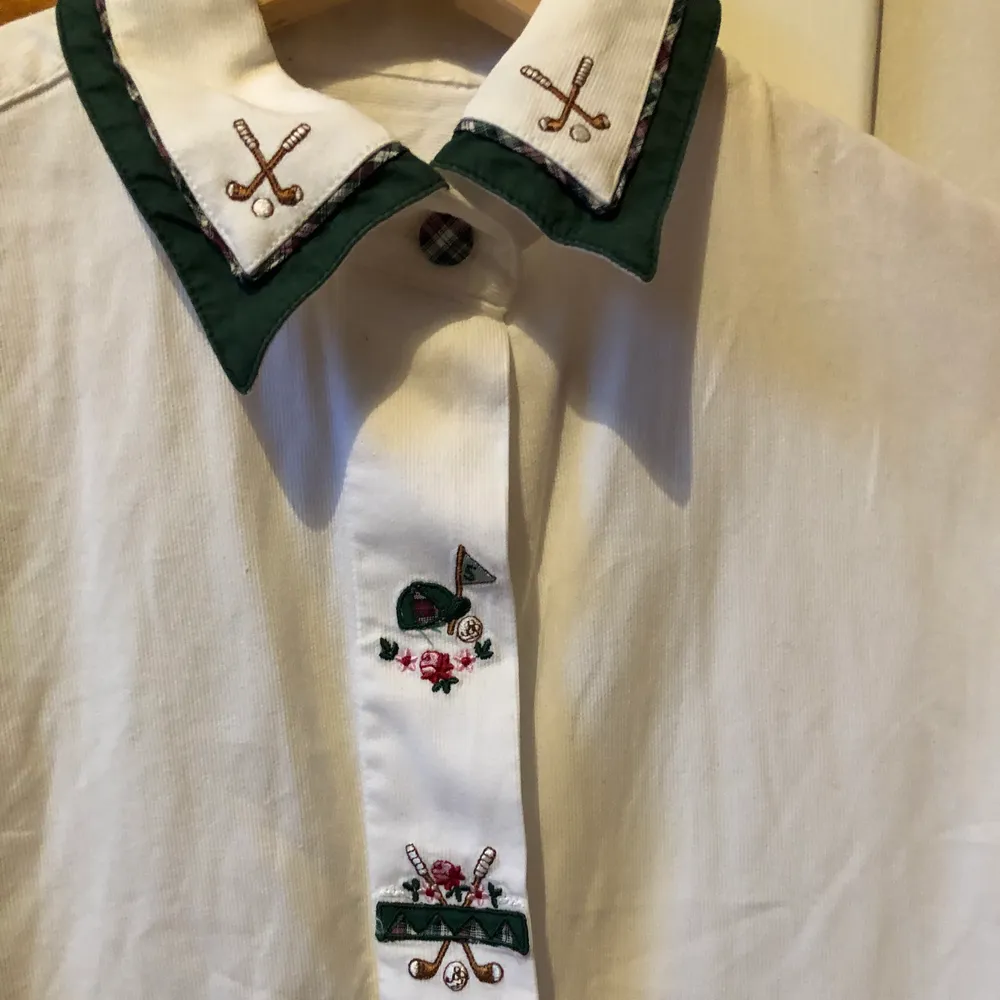En vit skjorta med golfbrodyr. Det saknas en del vita ”gömda” knappar som är lätta att ersätta. Köpt second hand för 100 spänn men har aldrig använt. Ingen märkning eller storlek (handsydd?) men passar strl M. Köparen står för frakt. . Skjortor.