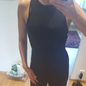  - Svart jumpsuit i blankt svart material med som som markerar midjan. Aldrig använd.    Finns i Helsingborg men kan skickas mot fraktkostnad