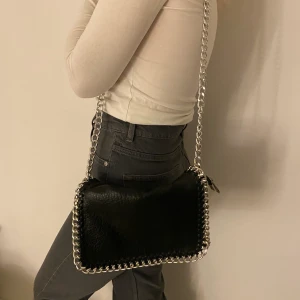 Svart väska  - Svart axelremsväska Tiamo i en större modell, frakt tillkommer 