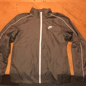 Nike - Skicken är bra köpte den för en månad sen men använder den aldrig och måttet är bra. Den sitter bra och skönt och den är beige. Det är typ en regnjacka men utan luva och den skyddar mot regn bra. De är nike och köpt från nike. Storleken är S.